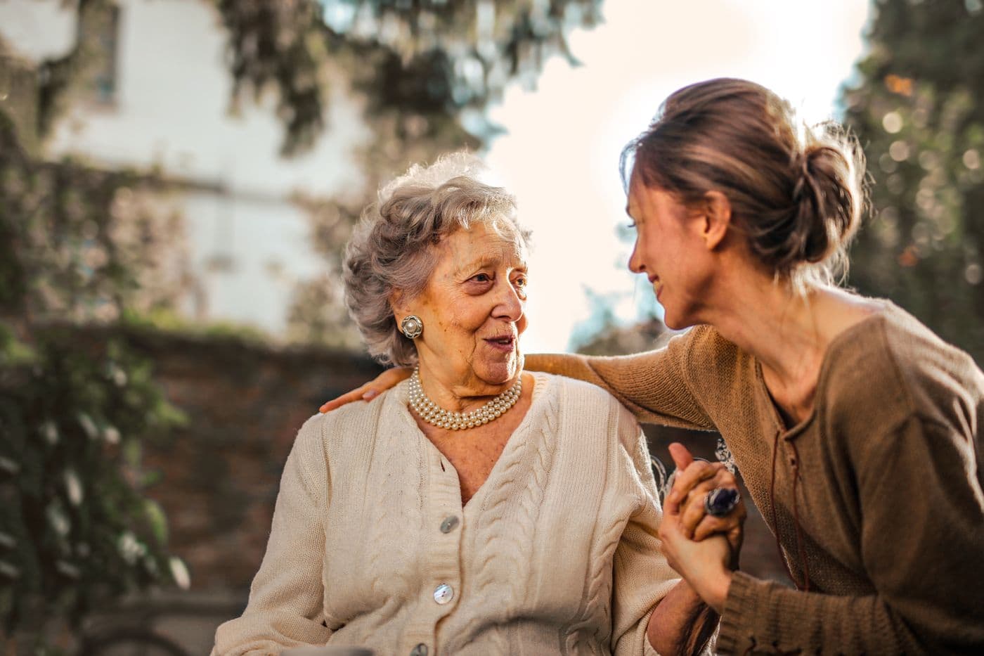 A caregiver and older adult sharing a warm outdoor moment of support