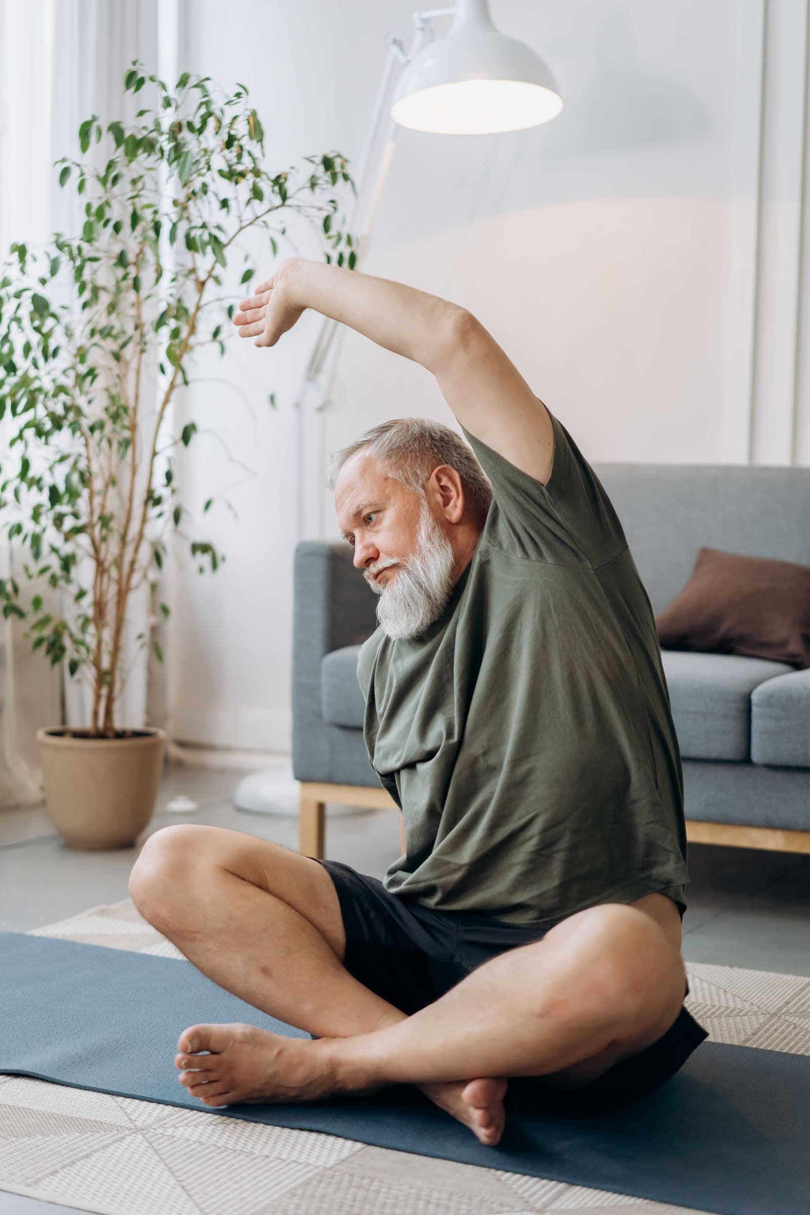 An older adult stretching on a yoga mat in a bright living room