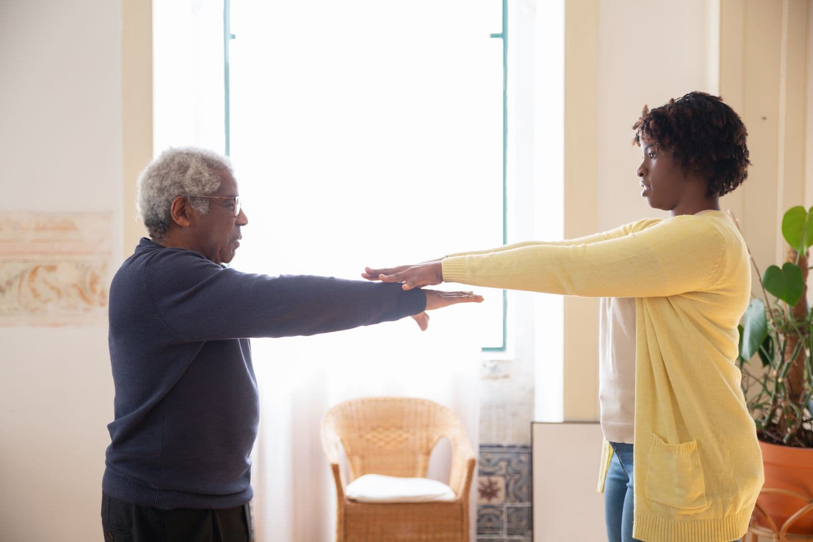 Fitness specialist guiding an older adult through a calm balance exercise in a bright home