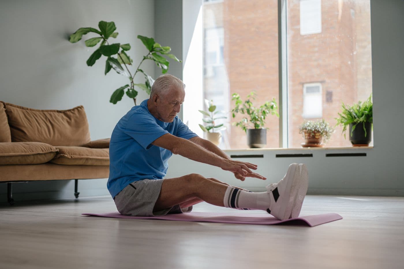 An older adult performing a seated stretch on a mat at home